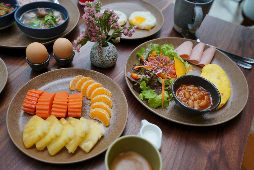 A generously styled breakfast spread with fruit, salad, eggs, sausage, beans, and drinks.