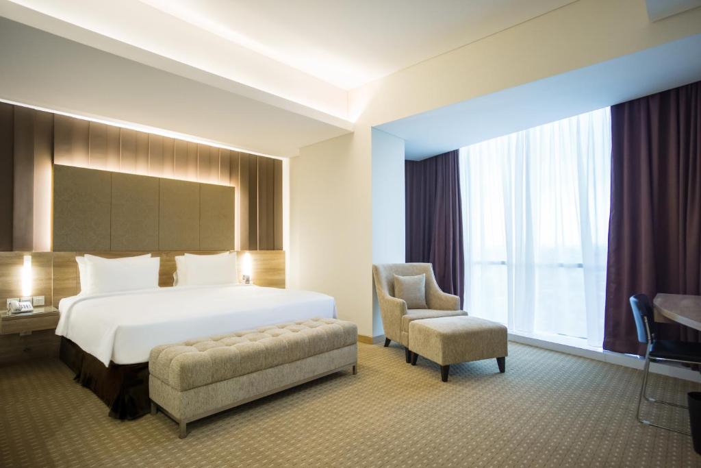 um quarto de hotel com uma cama e uma cadeira em Grand G7 Hotel Kemayoran em Jacarta