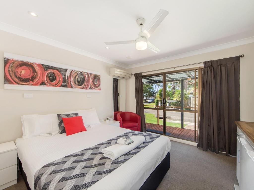 a bedroom with a large bed and a red chair at Narimba Motel in Port Macquarie