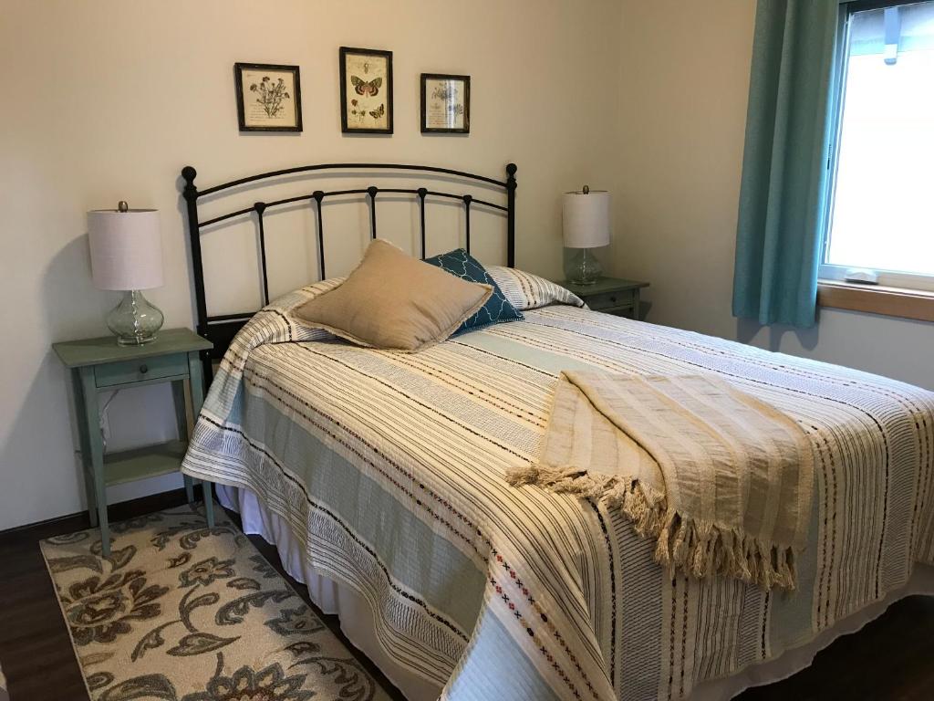 a bed in a bedroom with two tables and a window at Hoh Valley Cabins in Forks