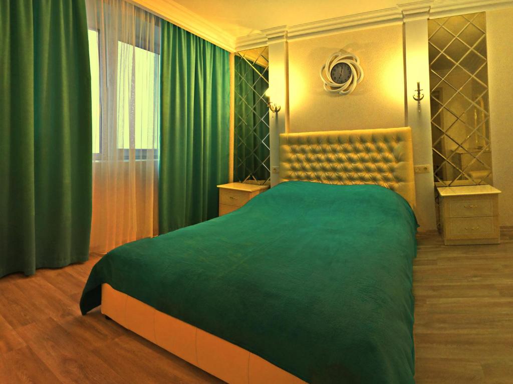 a bedroom with a large bed with a green blanket at ApartLux 2 in Chernihiv