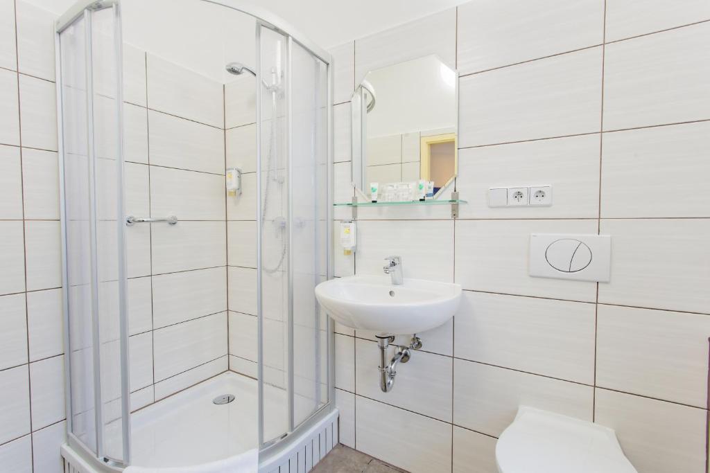 a white bathroom with a shower and a sink at Hotel &amp; Restaurant ,,Zur Alten Oder&quot; in Frankfurt-Oder in Frankfurt Oder