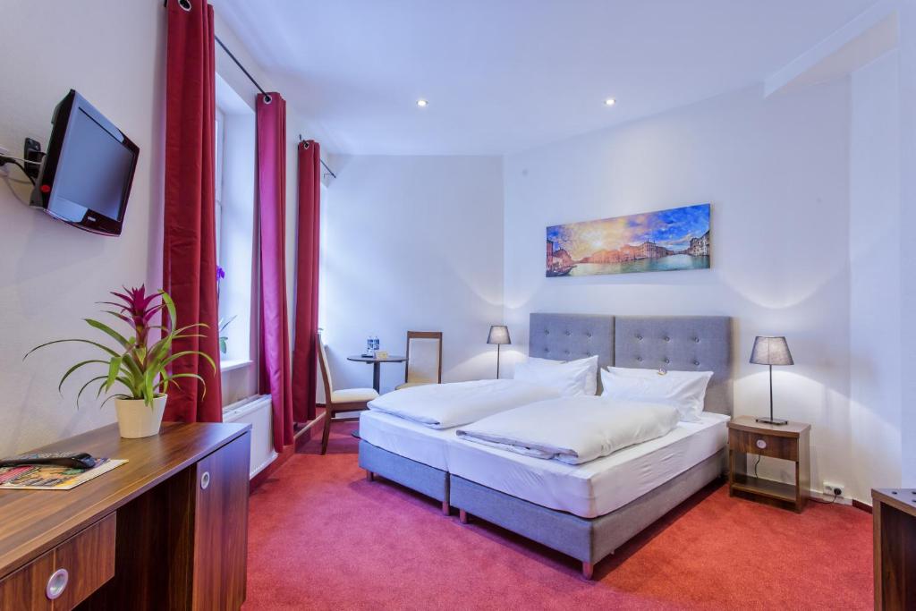 a bedroom with a large white bed and a tv at Hotel &amp; Restaurant ,,Zur Alten Oder&quot; in Frankfurt-Oder in Frankfurt Oder