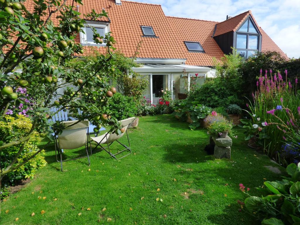 un jardin avec un pommier et des chaises en face d'une maison dans l'établissement Wissant l'Opale, à Wissant
