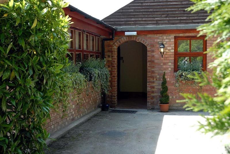 a brick house with a door and a courtyard at Hopbine House in Hereford