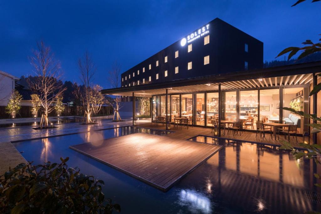 um edifício com uma piscina em frente à noite em Solest Takachiho Hotel em Takachiho