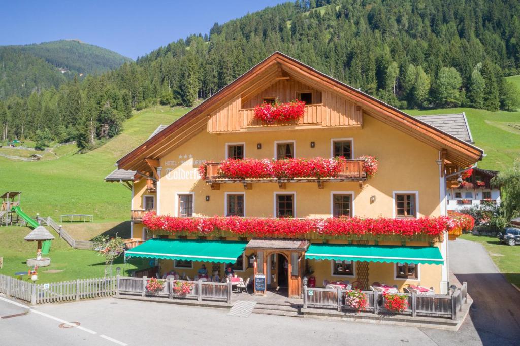 a building with flowers on the side of it at Hotel Tolderhof in San Candido
