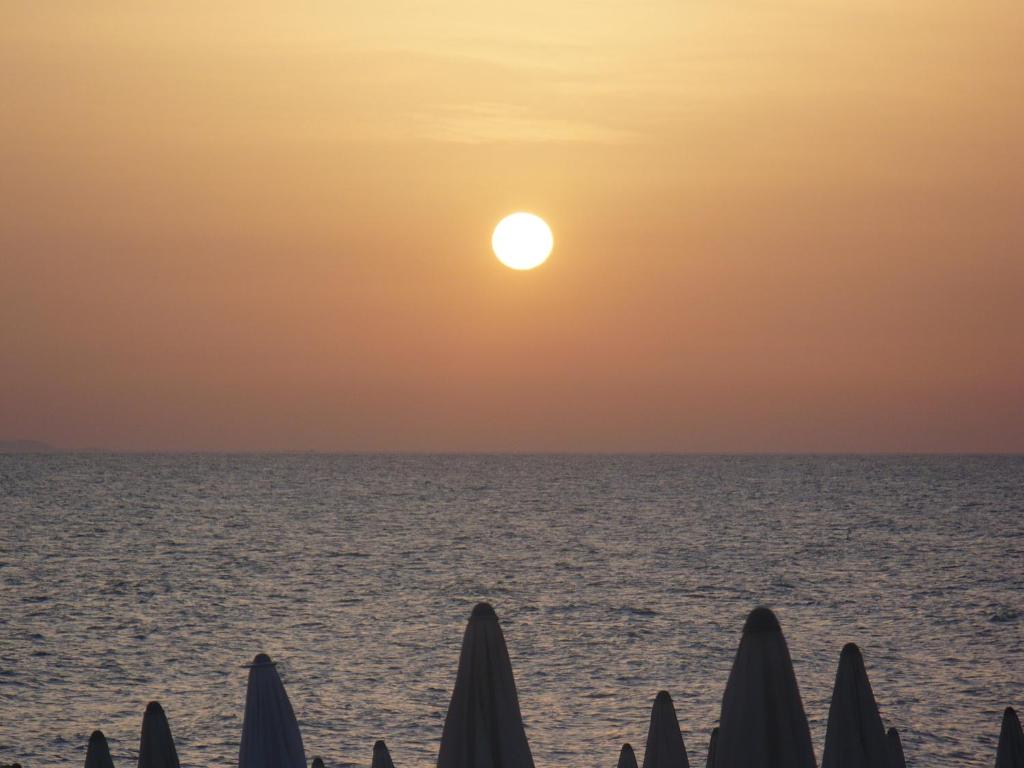 un tramonto sull'oceano con un gruppo di ombrelli di Marina Di Bibbona a Marina di Bibbona