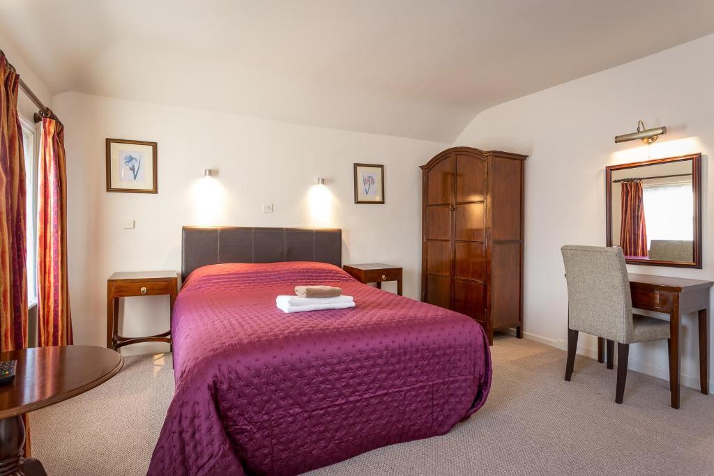 a bedroom with a bed and a table and a chair at The Abbey Hotel in Tewkesbury