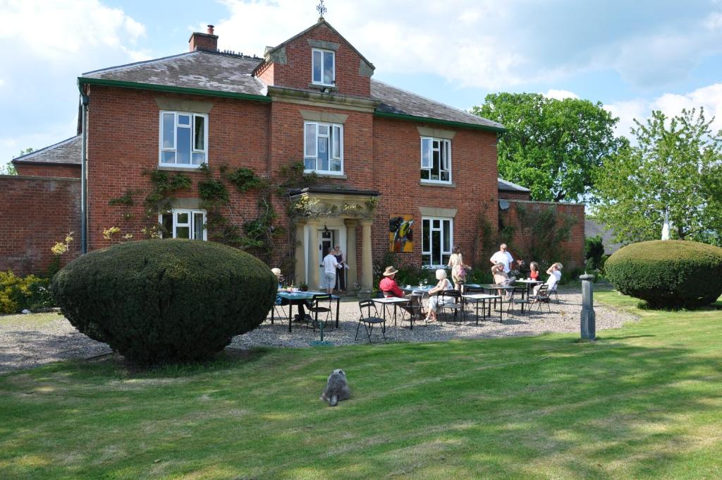 a group of people sitting at a table in front of a house at Mid Wales Arts B&B in Caersws