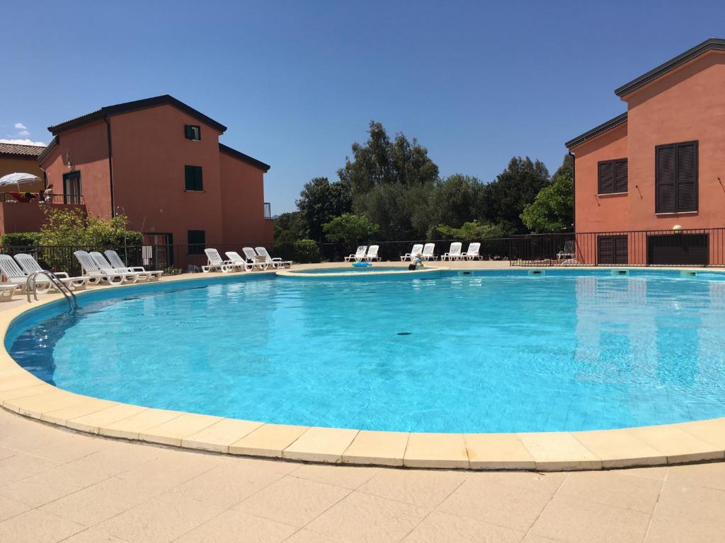 ein großer Pool mit Stühlen und ein Gebäude in der Unterkunft Terrazza SOLI MARE in Belgodère