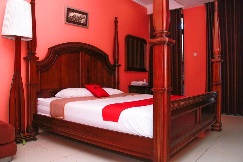 um quarto com uma cama grande e paredes vermelhas em RedDoorz @ Sersan Bajuri em Bandung