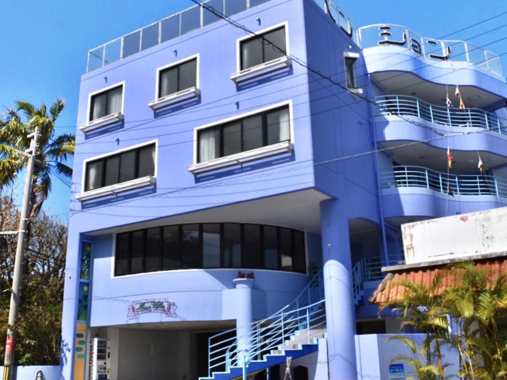 恩納的住宿－月光別墅飯店，带阳台的蓝色建筑,棕榈树