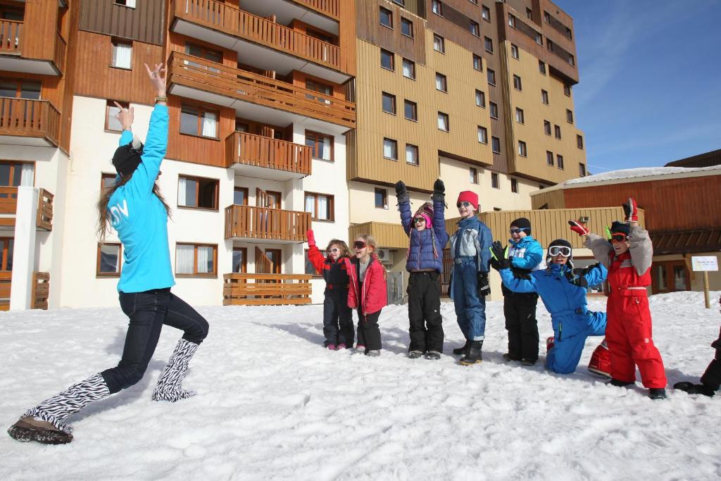 a group of children standing in the snow in front of a building at Hôtel Club mmv Les Bergers **** in L'Alpe-d'Huez