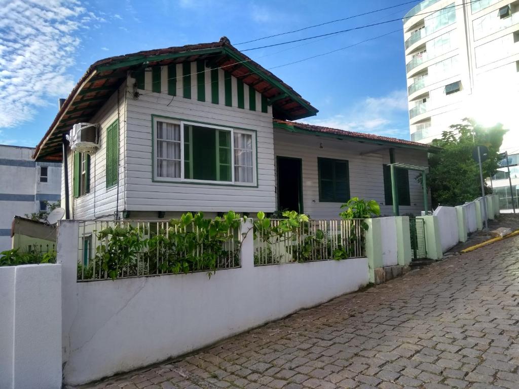 a white house with a fence on a street at Opa Haus - Pousada & Hostel in Itajaí