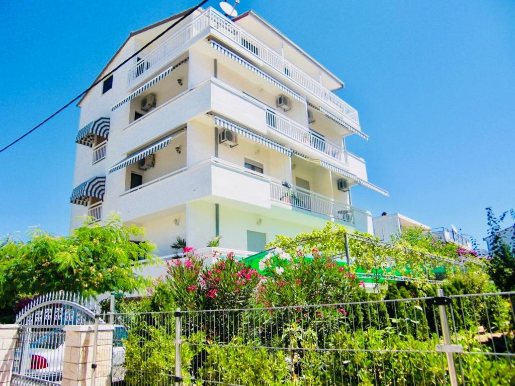 a tall white building with plants in front of it at Apartments Ruza in Kaštela
