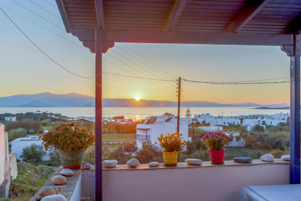 a view of a sunset from a balcony with flowers at Nicki's House in Agia Anna Naxos