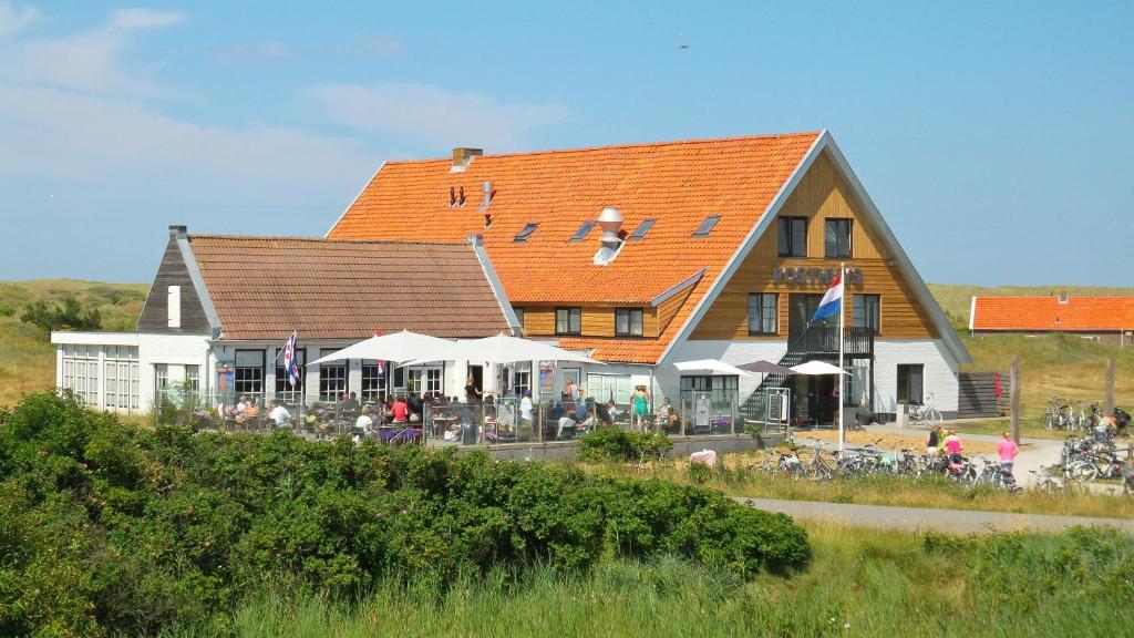 ein großes Haus mit Leuten, die draußen sitzen in der Unterkunft Hotel Posthuys Vlieland in Oost-Vlieland