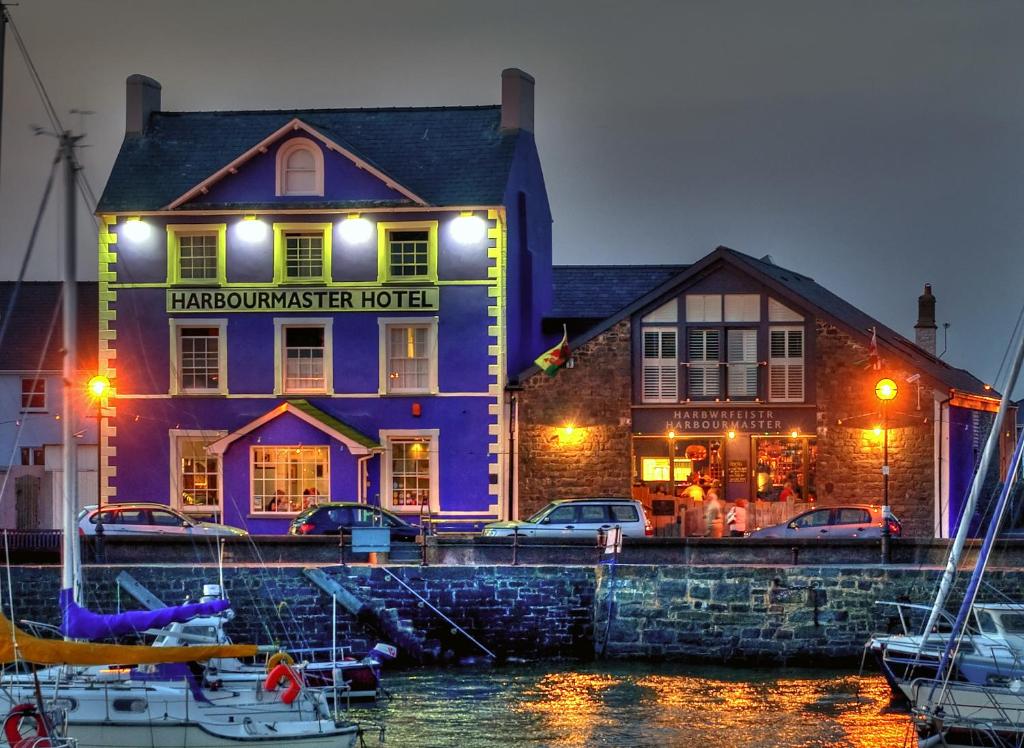 a purple building with boats in front of a marina at Harbourmaster Hotel in Aberaeron