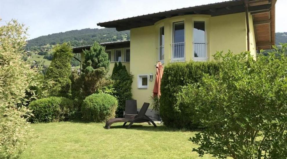 a yellow house with a chair in the yard at Ferienhaus Scharl in Schruns