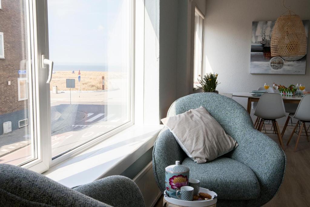 a living room with a chair and a window at kustappartementenkatwijk in Katwijk aan Zee