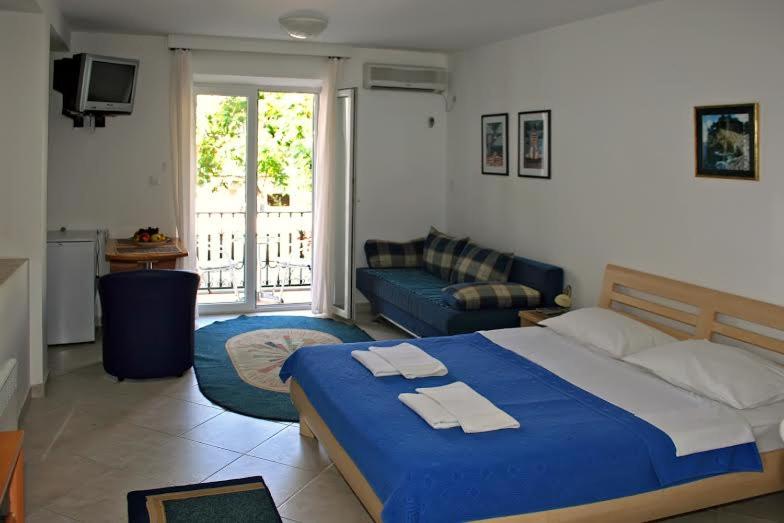 a bedroom with a blue bed and a living room at Casa M & S in Petrovac na Moru