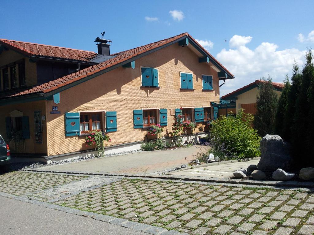 ein großes Gebäude mit blauen Fenstern und einer Kopfsteinpflastereinfahrt in der Unterkunft Gästehaus-Einkehr in Oberreute