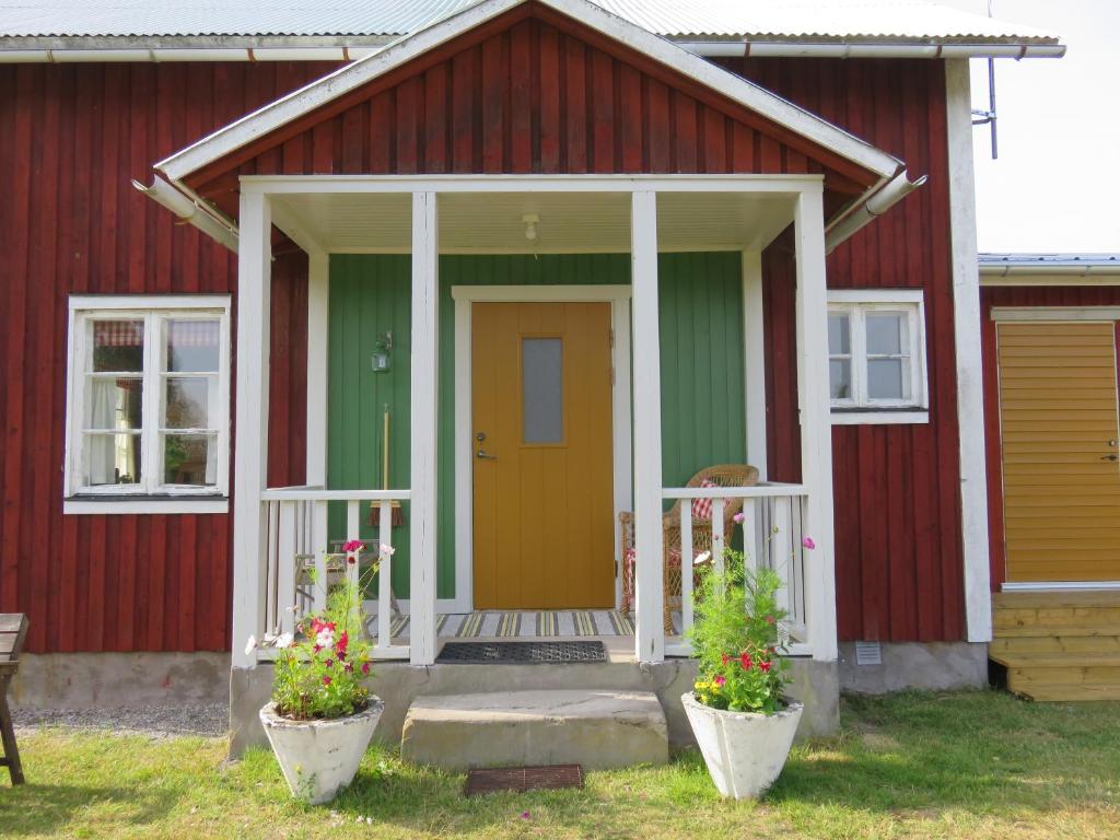 ein rotes und grünes Haus mit gelber Tür in der Unterkunft Stuga på landet in Gunnarskog