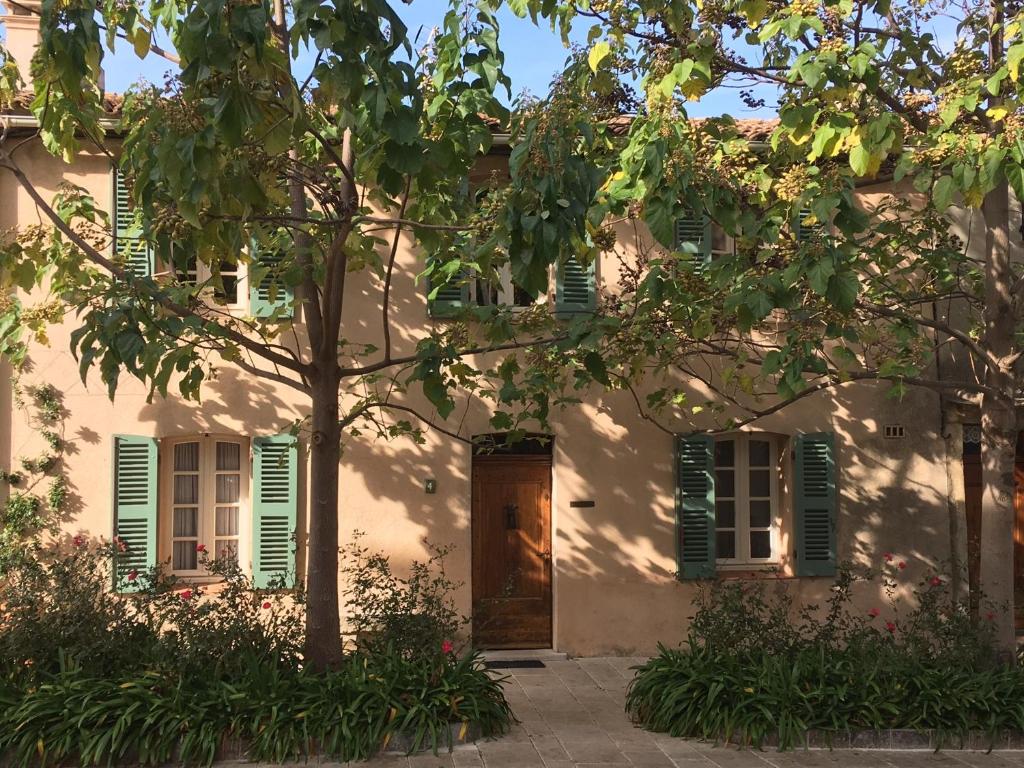 a house with green shutters and a tree at Maison au cœur du Village in Gassin