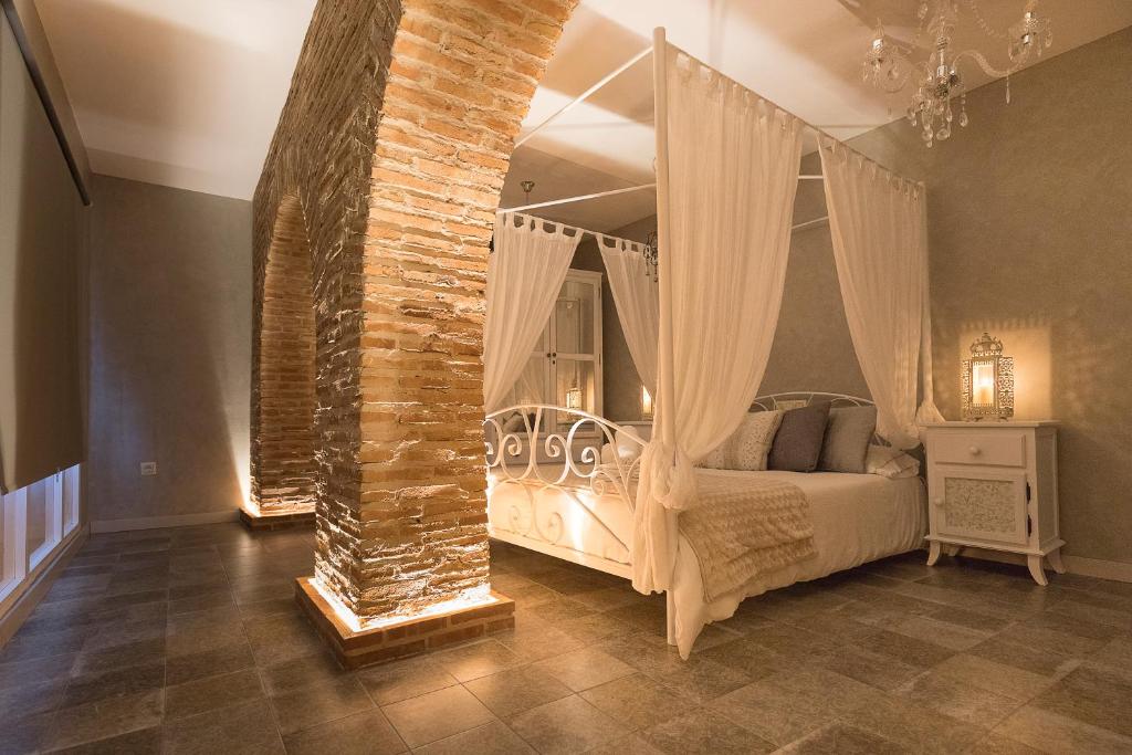 - une chambre avec un lit à baldaquin et un mur en briques dans l'établissement Hotel Posada de las Cuevas, à Arcos de la Frontera