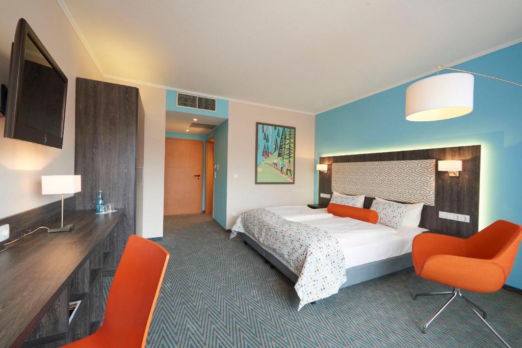 a hotel room with a bed and two orange chairs at Trans World Hotel Auefeld in Hannoversch Münden