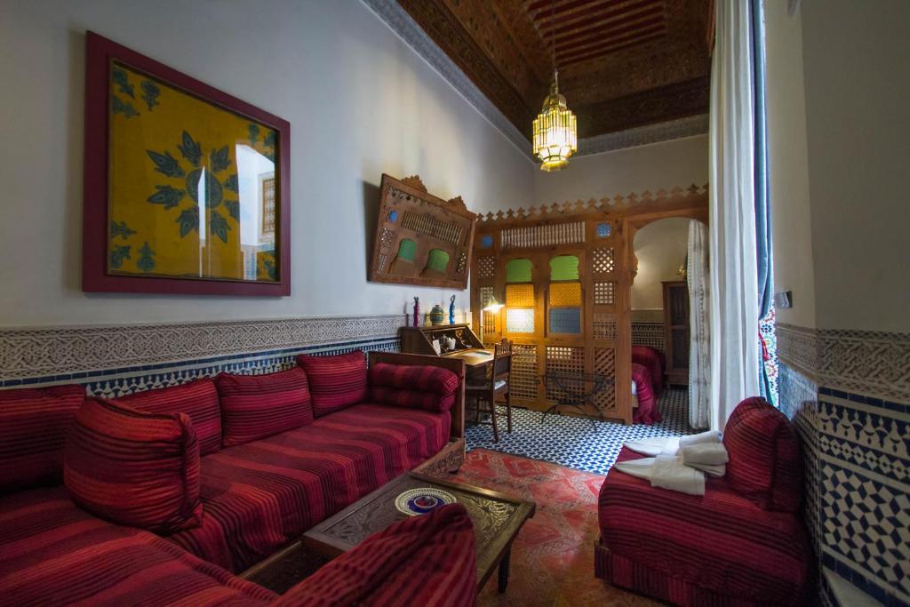 a living room with a red couch and two chairs at Riad Dar Cordoba in Fès