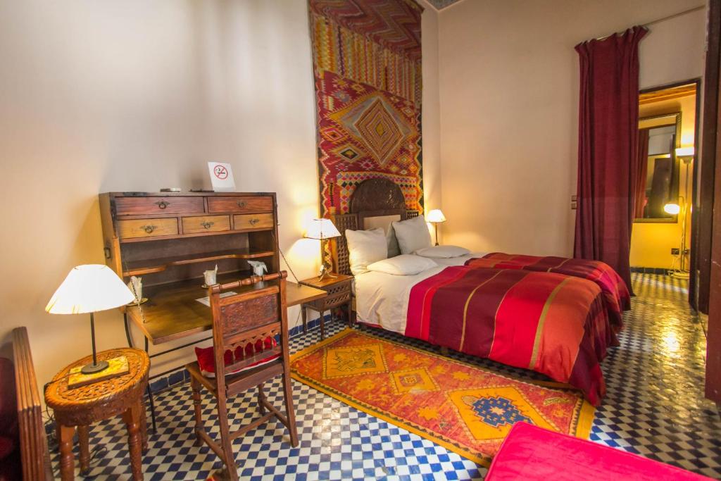 a bedroom with a bed and a desk and a piano at Riad Dar Cordoba in Fès
