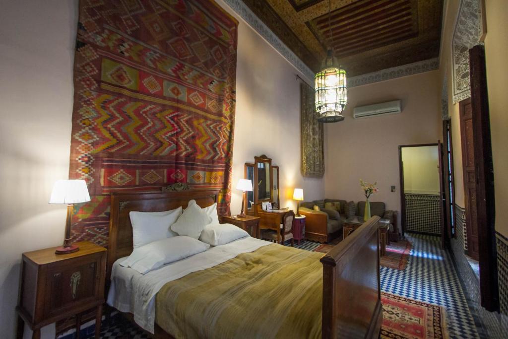 a bedroom with a large bed and a living room at Riad Dar Cordoba in Fès