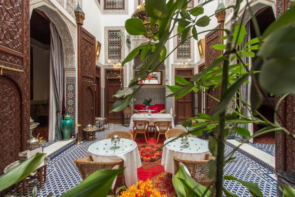 a room with two tables and chairs and plants at Riad Dar Cordoba in Fès