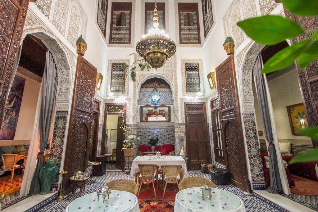 a room with a table and chairs and a chandelier at Riad Dar Cordoba in Fès