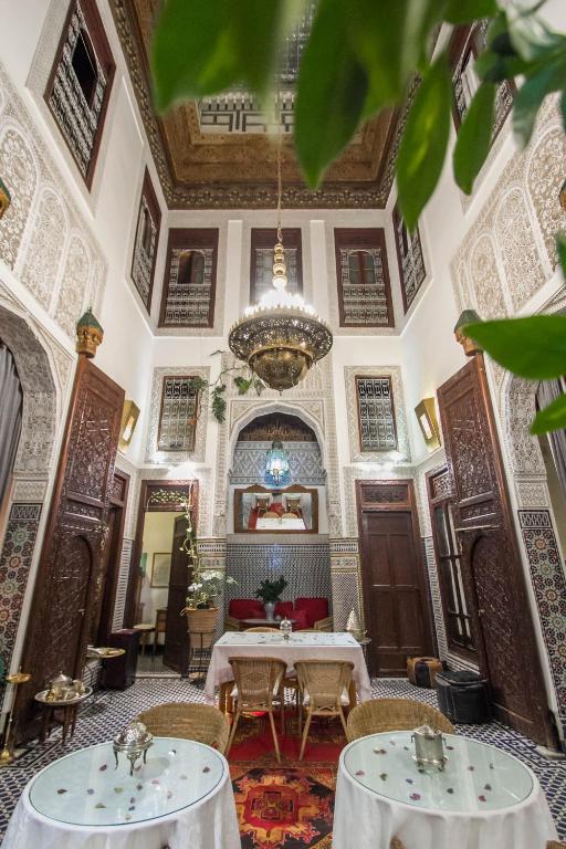a large room with two tables and a chandelier at Riad Dar Cordoba in Fès
