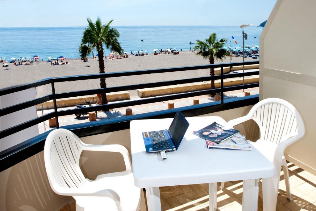 a table with a laptop on a balcony overlooking the beach at Polifemo in Letojanni