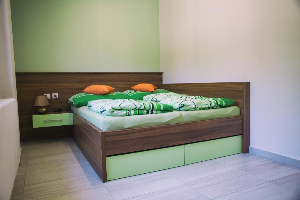 een slaapkamer met een bed met groene lakens en oranje kussens bij Penzion JaRo in Hodonín
