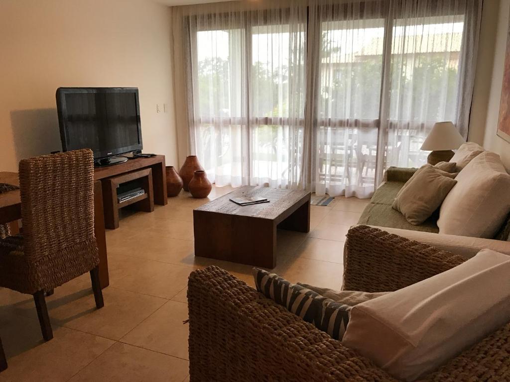 a living room with a couch and a tv at Reserva Imbassai in Imbassai