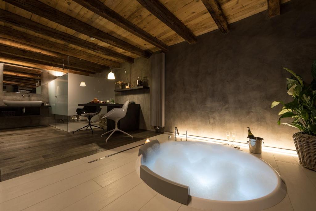 a large white bath tub in a room with a table at Relais Bondaz in Aosta