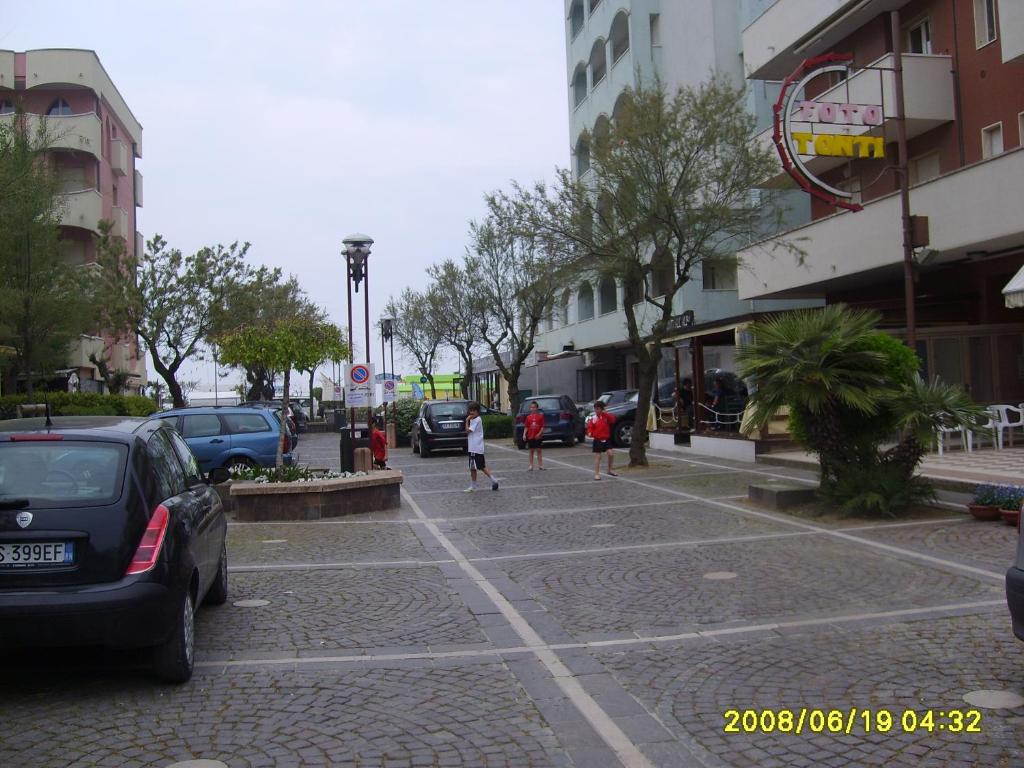 una strada con macchine parcheggiate e gente che cammina per strada di Appartamento Cinzia a Misano Adriatico