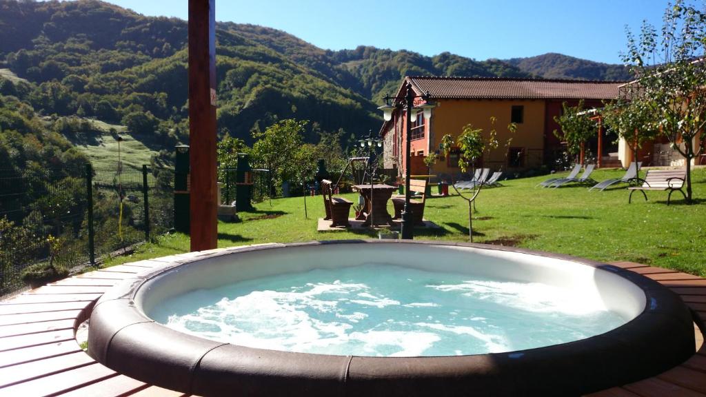 bañera de hidromasaje en una terraza con vistas a un patio en Apartamentos Rurales Balcón Real Senda del Oso, en Campiello