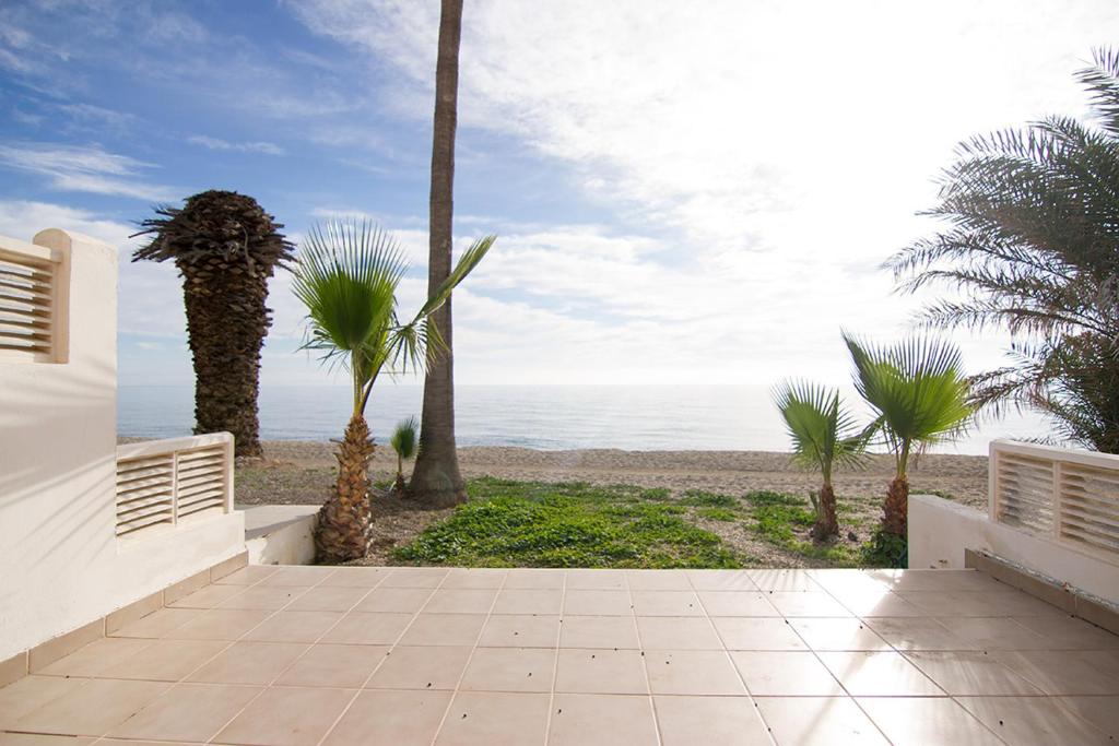 een loopbrug naar een strand met palmbomen en de oceaan bij Bungalow de Lujo a pie de playa en Aguadulce in Aguadulce