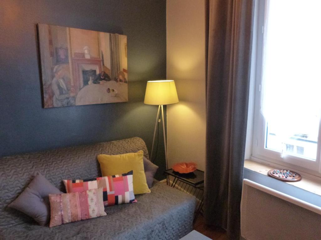 - un salon doté d'un canapé avec des oreillers et d'une fenêtre dans l'établissement Chambre d'hôtes La grotte de Voltaire, à Nantes