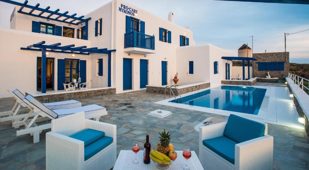 a villa with a swimming pool and blue chairs at Mykonos Pro-care Suites in Ano Mera