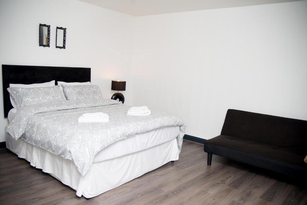 a bedroom with a white bed and a black chair at Liffey Suite in Dublin