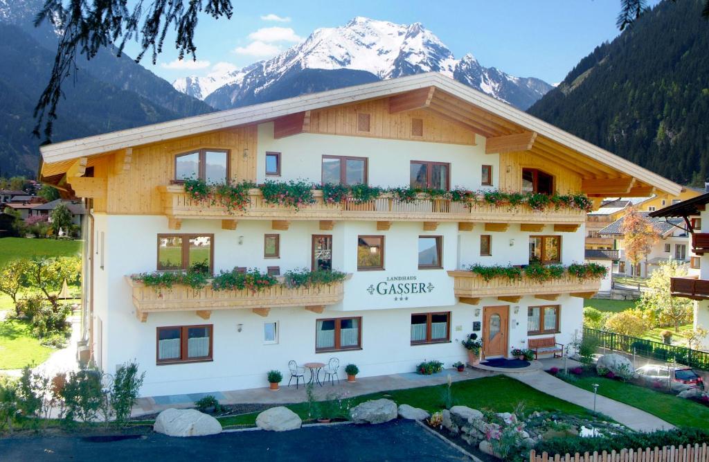 vistas a la parte delantera de un hotel con montañas en el fondo en Landhaus Gasser, en Mayrhofen