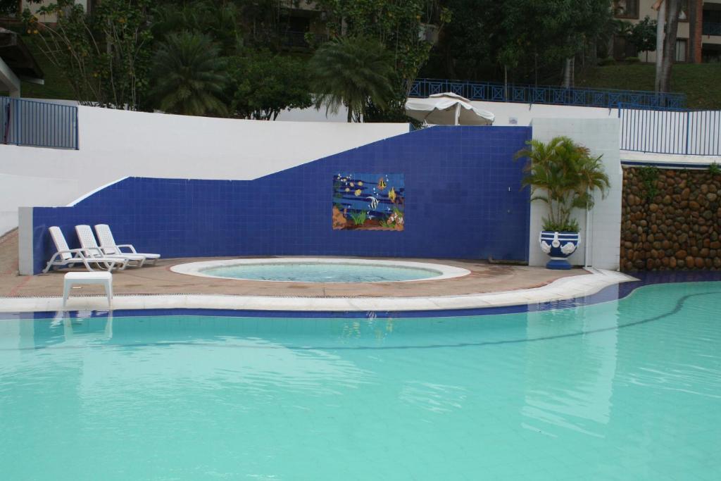 a swimming pool with two chairs and a blue wall at girardot resort apto102 in Ricaurte