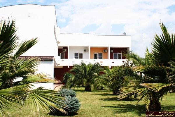 a house with palm trees in front of it at Hotel Sharmat in Pizunda